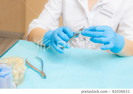 Orthodontic treatment. Alignment of the dentition or bite. Unrecognizable person. Hands in protective gloves close-up with a tool. Orthodontic treatment. Alignment of the dentition or bite. Unrecognizable person. Hands in protective gloves close-up with a tool. 92036631