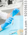 Orthodontic treatment. Alignment of the dentition or bite. Unrecognizable person. Hands in protective gloves close-up with a tool. 92036633