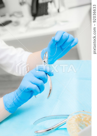 Orthodontic treatment. Alignment of the dentition or bite. Unrecognizable person. Hands in protective gloves close-up with a tool. Orthodontic treatment. Alignment of the dentition or bite. Unrecognizable person. Hands in protective gloves close-up with a tool. 92036633