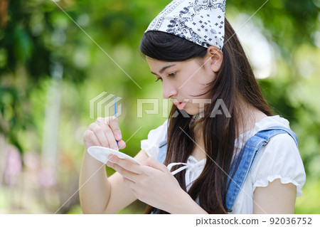 Young asian woman pianting and relaxing in park. Young asian woman pianting and relaxing in park. 92036752