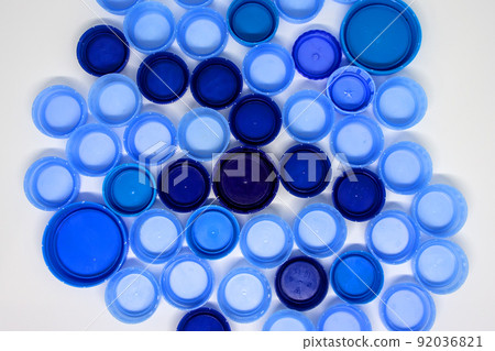 Dark and light blue plastic bottle caps on white background. Flat lay, view from above 92036821