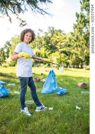 Cute young volunteer cleaning the park from plastic garbage Cute young volunteer cleaning the park from plastic garbage 92037494