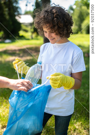 Someone helping a curly-haired teen to gather garbage Someone helping a curly-haired teen to gather garbage 92037500