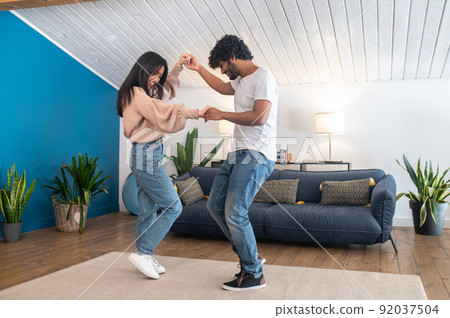 Cute young couple looking happy while dancing Cute young couple looking happy while dancing 92037504