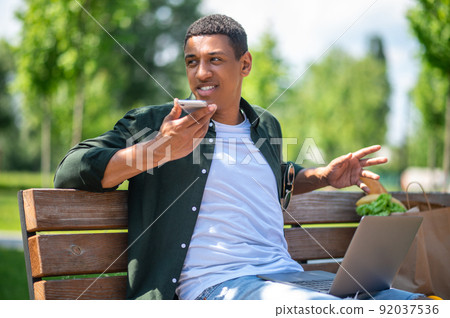 Man looking away saying message on smartphone Man looking away saying message on smartphone 92037536