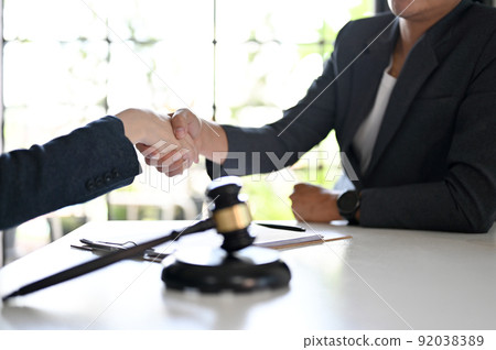 Female lawyer shaking hands to greeting her client, having a formal meeting Female lawyer shaking hands to greeting her client, having a formal meeting 92038389