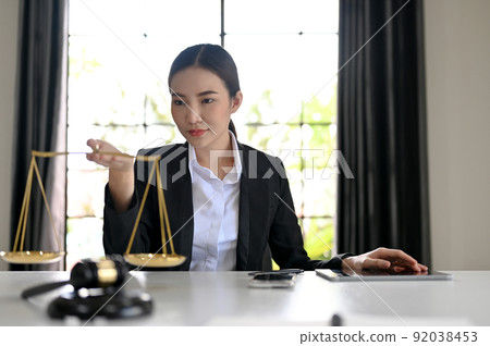 Beautiful Asian female lawyer or law consultant hold a scales of justice Beautiful Asian female lawyer or law consultant hold a scales of justice 92038453