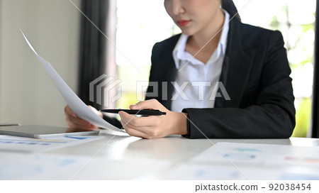 Concentrated female financial business worker analysing the financial report Concentrated female financial business worker analysing the financial report 92038454