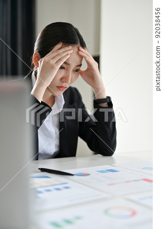 Stressed and serious Asian businesswoman or financial consultant reading a financial report Stressed and serious Asian businesswoman or financial consultant reading a financial report 92038456