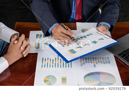 Two business leaders talk about charts, financial graphs showing results are analyzing and calculating planning strategies, business success building processes Two business leaders talk about charts, financial graphs showing results are analyzing and calculating planning strategies, business success building processes 92039276