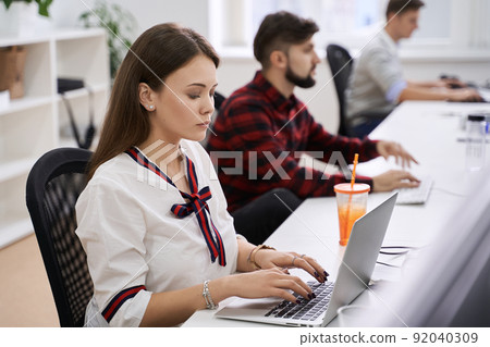 People working in modern IT office. Group of young and experienced programmers and software developers sitting at desks working on computers. Team at work. People working in modern IT office. Group of young and experienced programmers and software developers sitting at desks working on computers. Team at work. 92040309