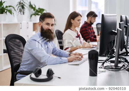 People working in modern IT office. Group of young and experienced programmers and software developers sitting at desks working on computers. Team at work. People working in modern IT office. Group of young and experienced programmers and software developers sitting at desks working on computers. Team at work. 92040310