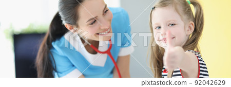 Girl being examined by pediatrician doctor, happy child show thumbs up gesture Girl being examined by pediatrician doctor, happy child show thumbs up gesture 92042629