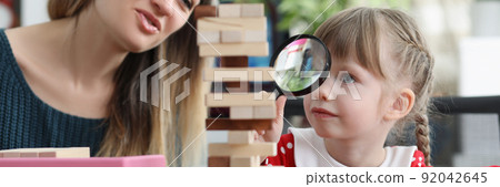 Cute little girl watch through magnifying glass on high wooden tower Cute little girl watch through magnifying glass on high wooden tower 92042645