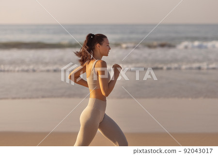 Female Runner Jogging During Outdoor Workout on the Beach Female Runner Jogging During Outdoor Workout on the Beach 92043017