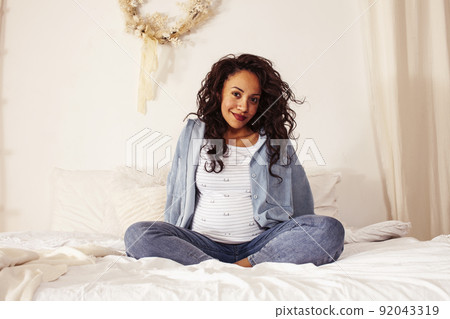 young pretty african american woman pregnant laying in bed, lifestyle people concept close up young pretty african american woman pregnant laying in bed, lifestyle people concept close up 92043319