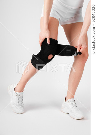 Knee Support Brace on leg isolated on white background. Elastic orthopedic orthosis. Anatomic braces for knee fixation, injuries and pain. Protective knee joint bandage sleeve. Trauma, rehabilitation. 92043326