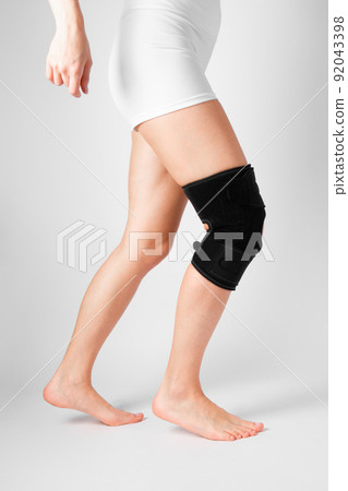 Knee Support Brace on leg isolated on white background. Elastic orthopedic orthosis. Anatomic braces for knee fixation, injuries and pain. Protective knee joint bandage sleeve. Trauma, rehabilitation. 92043398