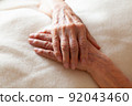 Senior woman's hands folded on a blanket 92043460