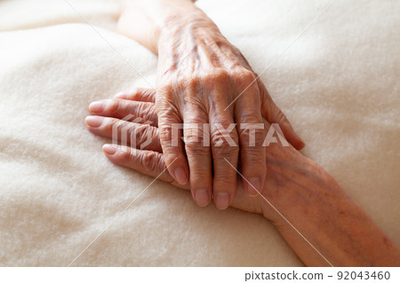 Senior woman's hands folded on a blanket 92043460