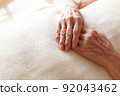 Senior woman's hands folded on a blanket 92043462
