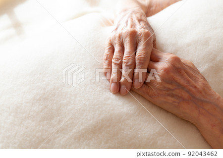 Senior woman's hands folded on a blanket 92043462