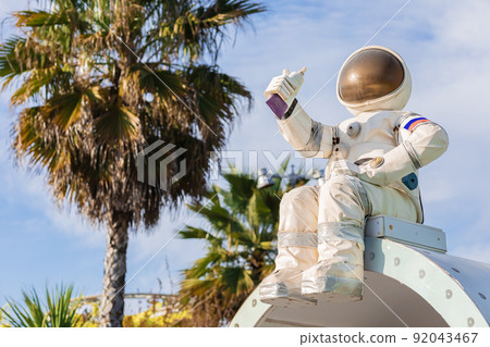 A figurine of an astronaut in a spacesuit holding a tube of food in his hand sits against the backdrop of palm trees and the sky in a south park 92043467