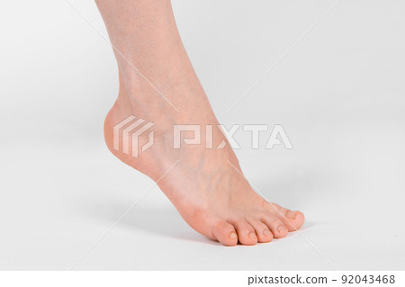 Barefoot and legs isolated on white background. Closeup shot of healthy beautiful female feet. Health and beauty concept. Side view of human foot ream with neutral manicure or pedicure. Sole of foot. 92043468