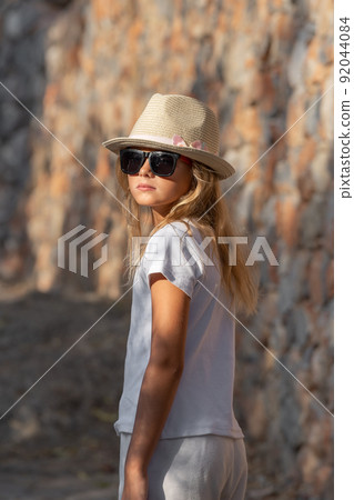 A beautiful young girl with blond hair turned around and looked at the camera. 92044084