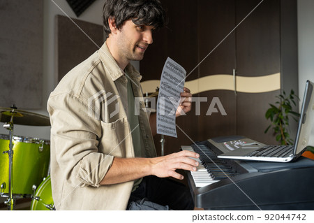 Man gives piano lesson via laptop and explains concept 92044742