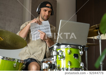 Man gives drum lesson via laptop. Guy demonstrates notes Man gives drum lesson via laptop. Guy demonstrates notes 92044778