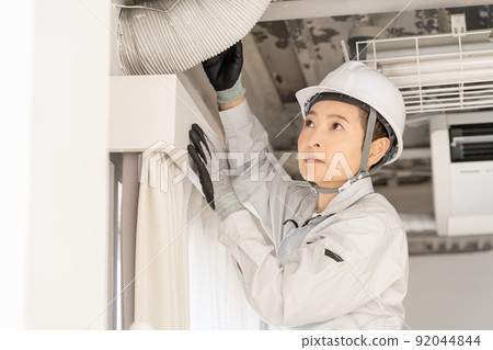 Middle-aged female worker inspecting ducts Middle-aged female worker inspecting ducts 92044844