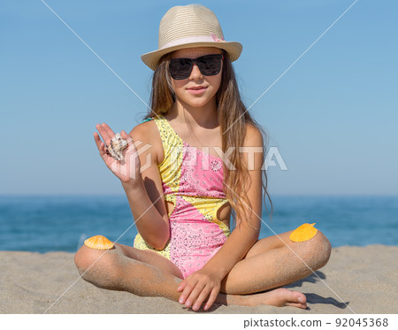 Portrait of a girl 10 years old on the beach with seashells. Portrait of a girl 10 years old on the beach with seashells. 92045368