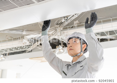 Middle-aged female worker checking the air conditioner Middle-aged female worker checking the air conditioner 92045901