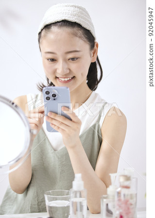 Young woman looking at her smartphone in the living room 92045947
