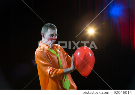Circus ?lown performs number. A man in a clown outfit with a balloon 92046014