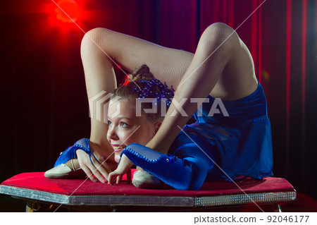 A girl with a flexible body. Performs a circus artist. Circus gymnast. Balancing act. The child performs an acrobatic trick A girl with a flexible body. Performs a circus artist. Circus gymnast. Balancing act. The child performs an acrobatic trick 92046177