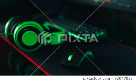 Gaming wireless accessories with green backlight next to headphones Gaming wireless accessories with green backlight next to headphones 92047082