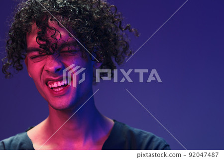 Stylish tanned curly man in black t-shirt looks at camera posing isolated on color pink blue studio background. Cool fashion offer. Virtual Reality New Collection concept. Copy space for ad Stylish tanned curly man in black t-shirt looks at camera posing isolated on color pink blue studio background. Cool fashion offer. Virtual Reality New Collection concept. Copy space for ad 92047487