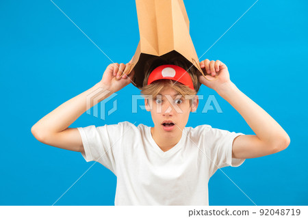 Shocked teen boy with paper bag over head. Teenager holding paper bag over the head posing in studio. Guy pulling paper bag over head. Shocked teen boy with paper bag over head. Teenager holding paper bag over the head posing in studio. Guy pulling paper bag over head. 92048719
