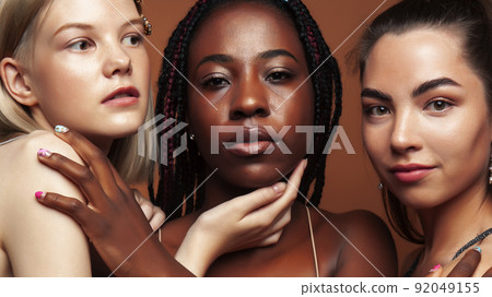 young pretty african and caucasian women posing cheerful together on brown background, lifestyle diverse nationality people concept close up young pretty african and caucasian women posing cheerful together on brown background, lifestyle diverse nationality people concept close up 92049155