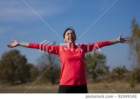 Cheerful athletic senior woman. Positive elderly woman is doing exercises. Portrait of a sporty elderly woman in the park 92049168