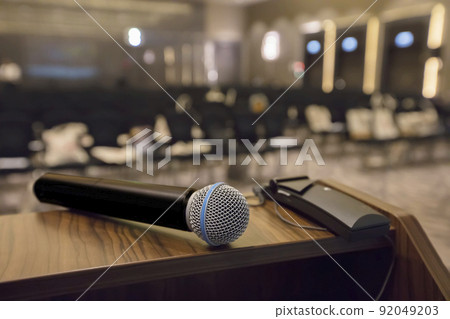 There is a microphone on the table against the background of an empty hall. There is a microphone on the table against the background of an empty hall. 92049203
