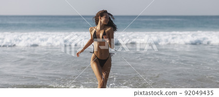 Happy bikini beach vacation woman running to ocean splashing water in freedom feeling. Happiness carefree lifestyle banner with blue ocean copy space 92049435