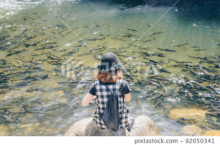 Back view of Asian women sitting and relaxing nearly the fresh water river in Kiriwong village in Nakhon Si Thammarat province of Thailand. 92050341