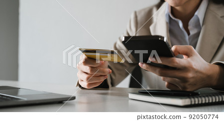 Close up female hands holding credit card and smartphone, young woman paying online, using banking service, entering information, shopping, ordering in internet store, doing secure payment Close up female hands holding credit card and smartphone, young woman paying online, using banking service, entering information, shopping, ordering in internet store, doing secure payment 92050774