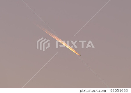 Distant passenger jet plane flying on high altitude on clear blue sky leaving white smoke trace of contrail behind. Air transportation concept Distant passenger jet plane flying on high altitude on clear blue sky leaving white smoke trace of contrail behind. Air transportation concept 92051663