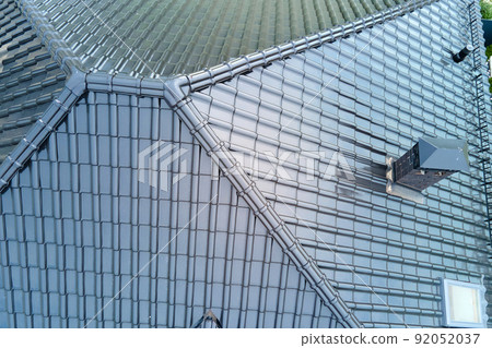 Closeup of house roof top covered with shiny ceramic shingles. Closeup of house roof top covered with shiny ceramic shingles. 92052037