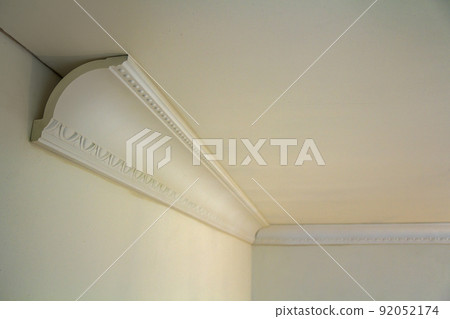 Close-up detail of decoration white molding connected with glue adhesive to wall and ceiling in interior room renovation and reconstruction. 92052174