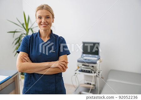 Smiling doctor, ultrasound specialist looking at camera on her workplace in clinic 92052236